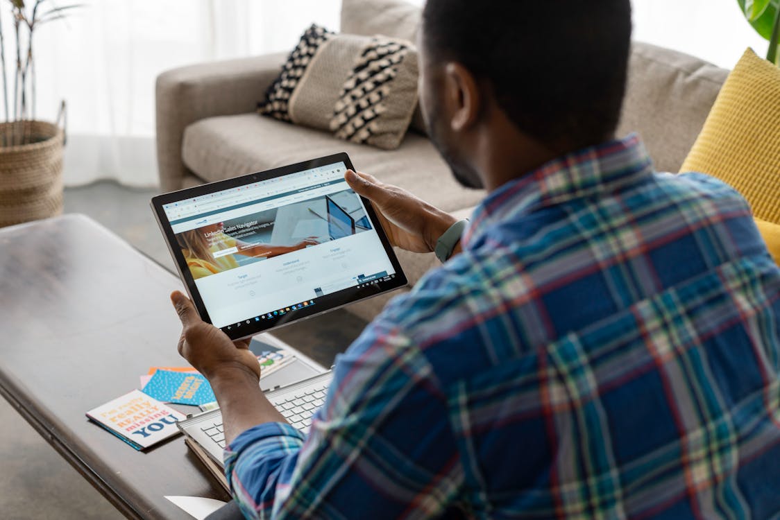 Free A Person in Blue Plaid Long Sleeves Holding a Tablet Stock Photo