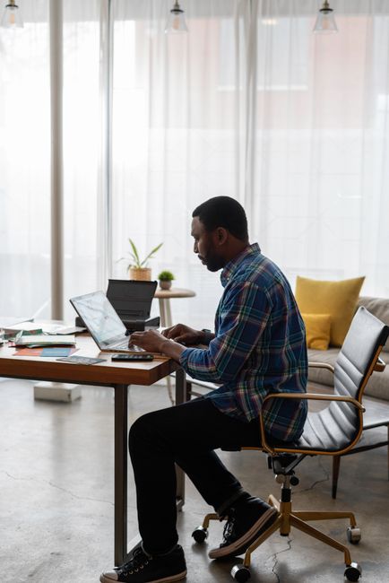 A focused individual working on a laptop in a bright and modern office setting. A focused individual working on a laptop in a bright and modern office setting.