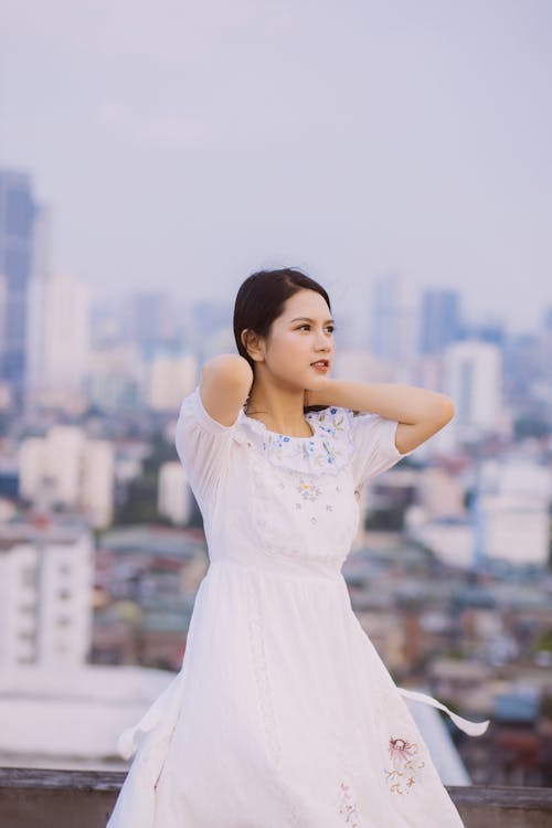 Free A Woman in White Dress Standing on the Rooftop Stock Photo