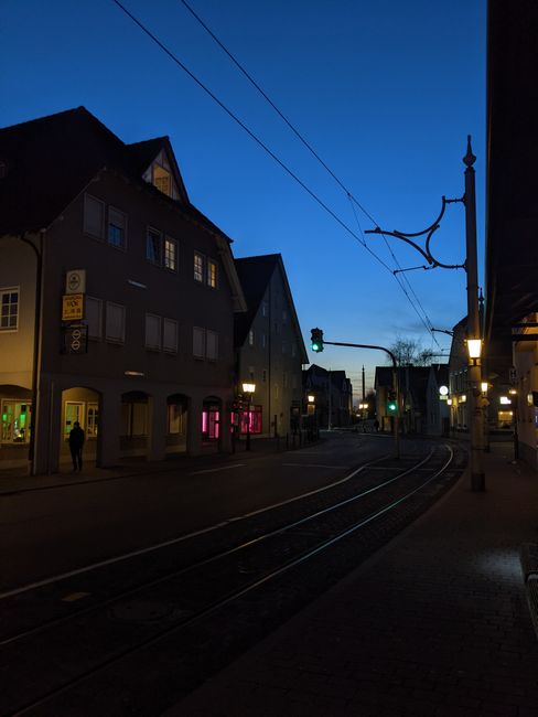 Roadway with tramway and old fashioned residential buildings located on street with streetlight and power lines in night time in city
