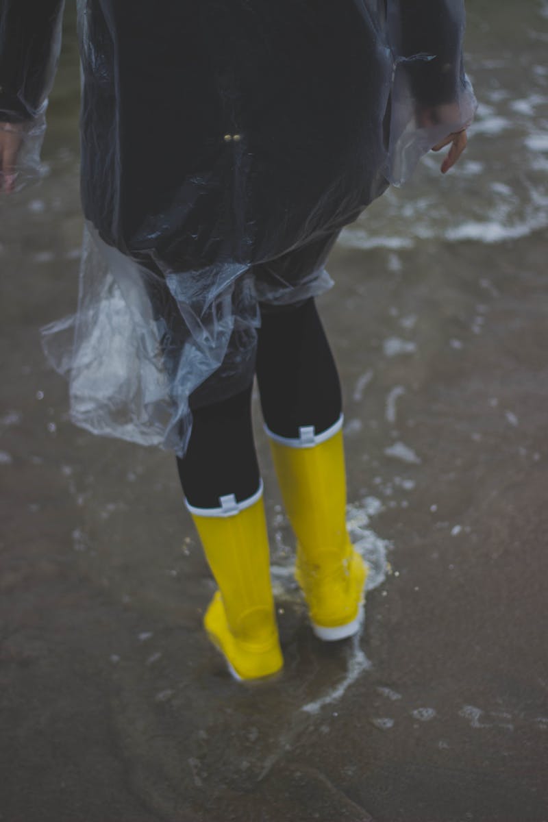 Person Wearing Clear Plastic Raincoat and Pair of Yellow Rainboots