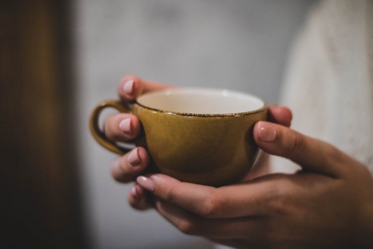 Person Holding Yellow Ceramic Cup