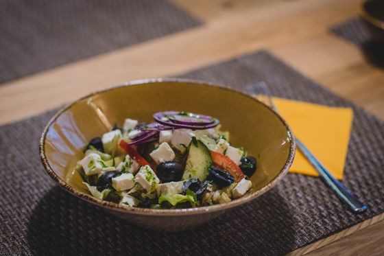 Ceramic bowl of Greek salad with feta, black olives, cucumber, tomato and red onion