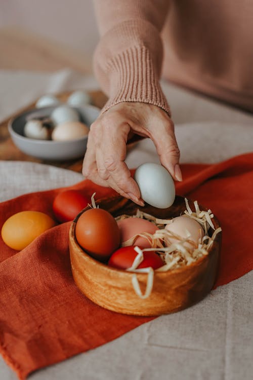 Free A Person Arranging Eggs on a Wooden Bowl Stock Photo