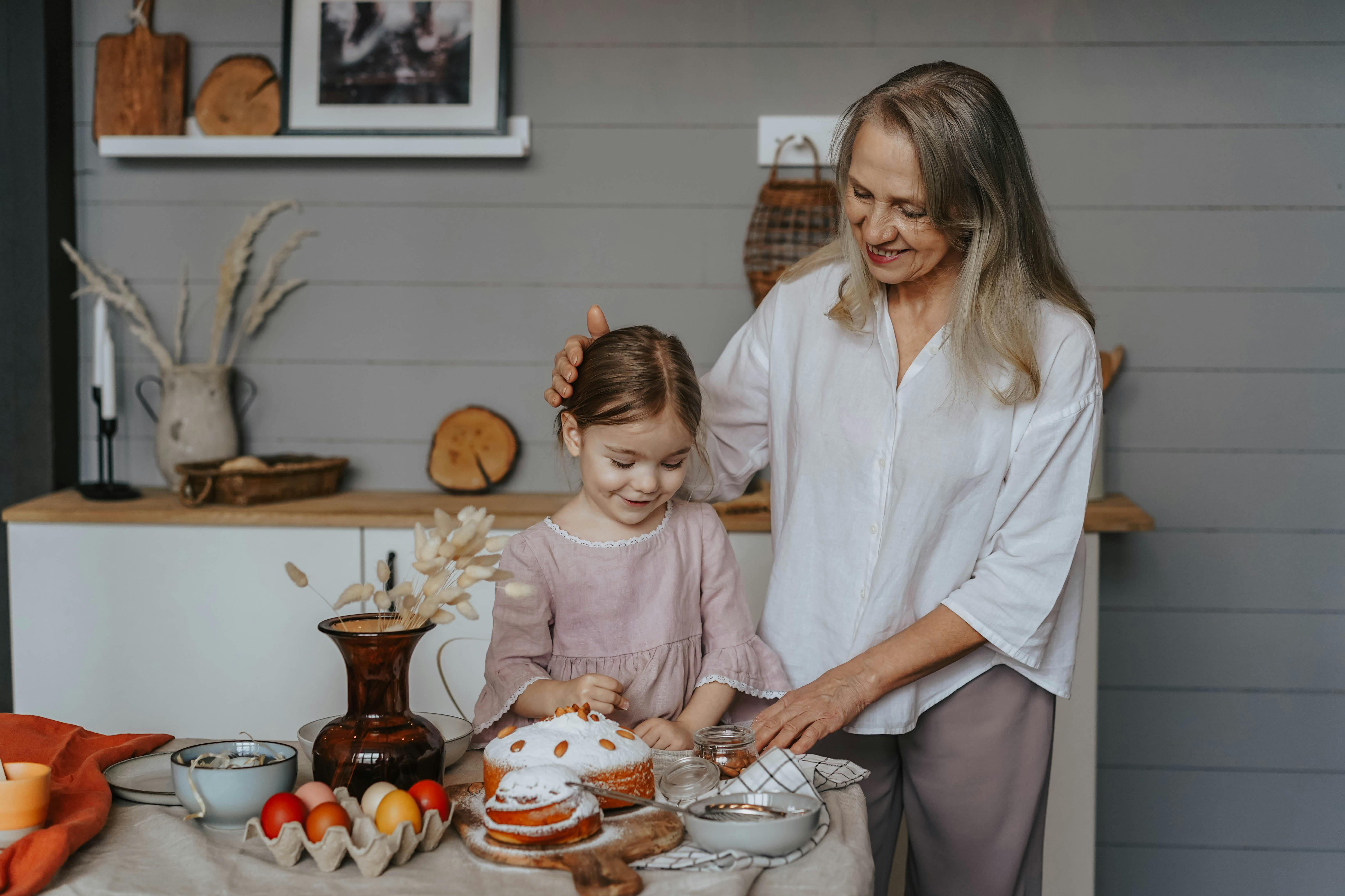 Grandmother and granddaughter decorating Easter eggs together at home, creating joyful memories.