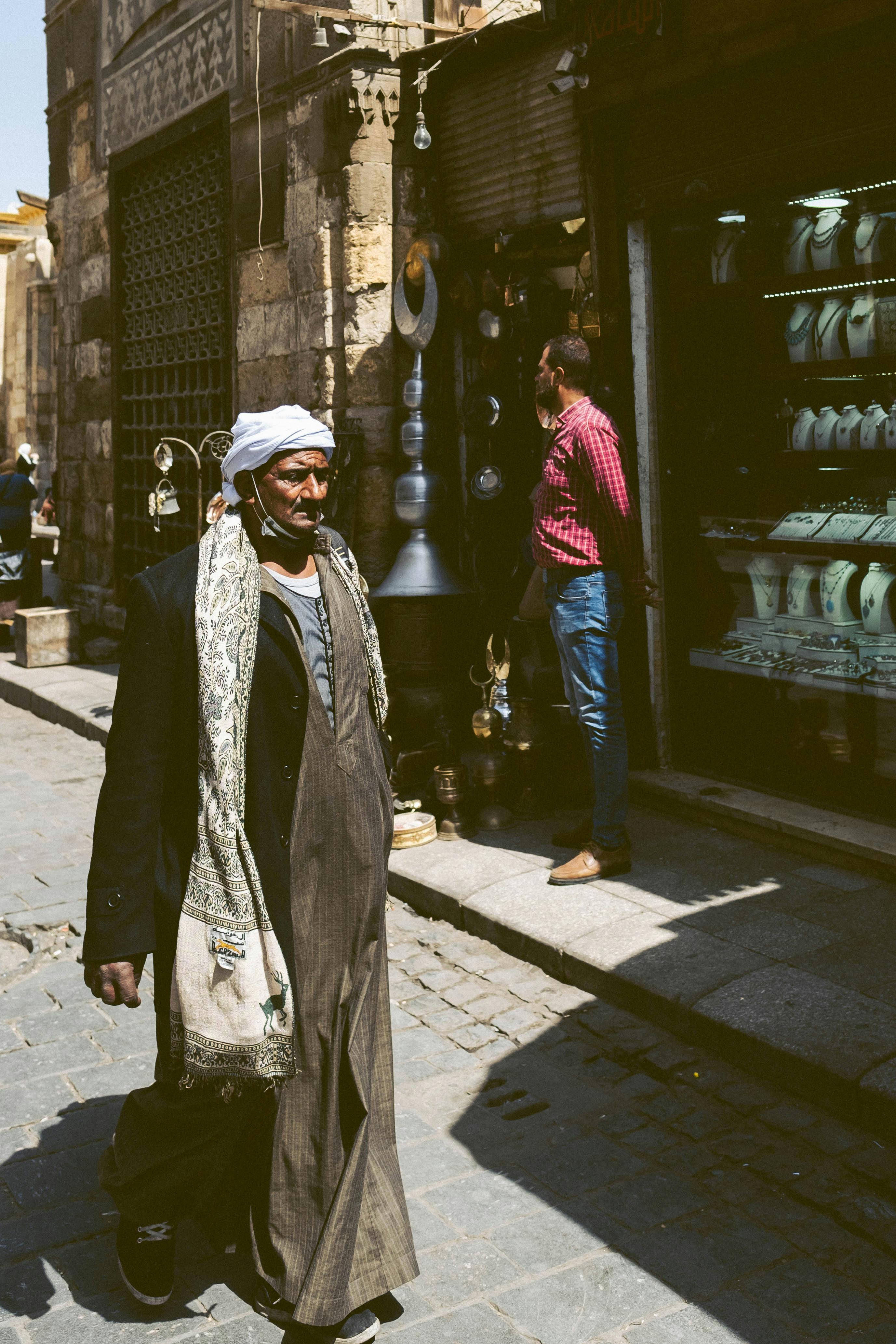 An elderly man in traditional attire walking along a market street in Cairo, Egypt.