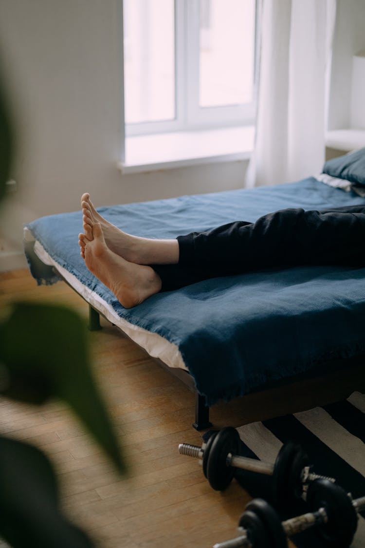 Feet Of A Person Lying In Bed