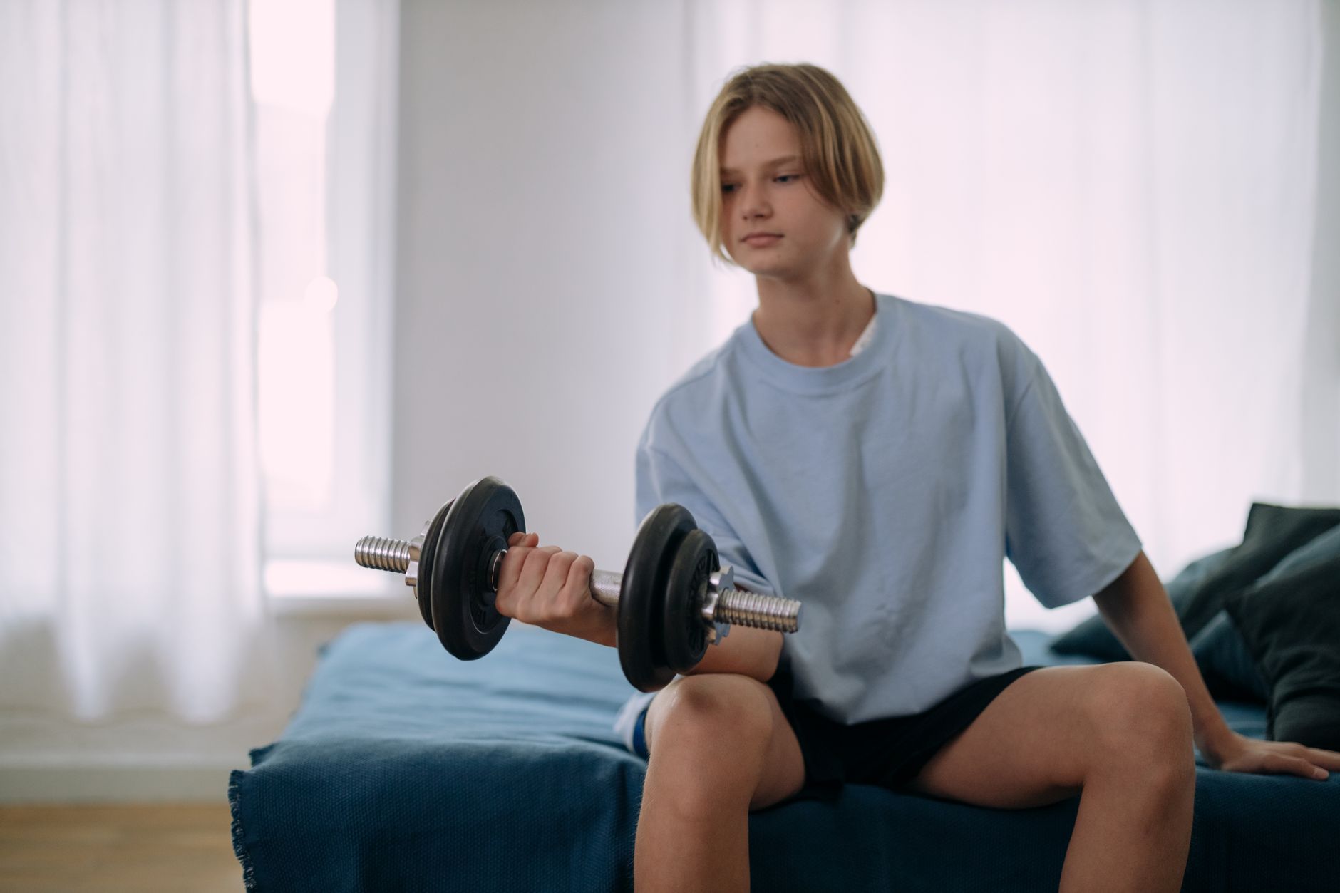 young teen lifting weights in his room