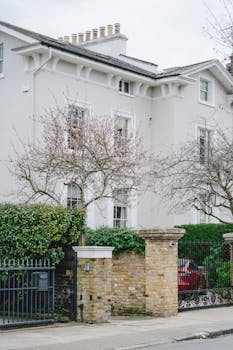A charming Victorian house with stone walls and blooming trees, located in a historic London neighborhood.