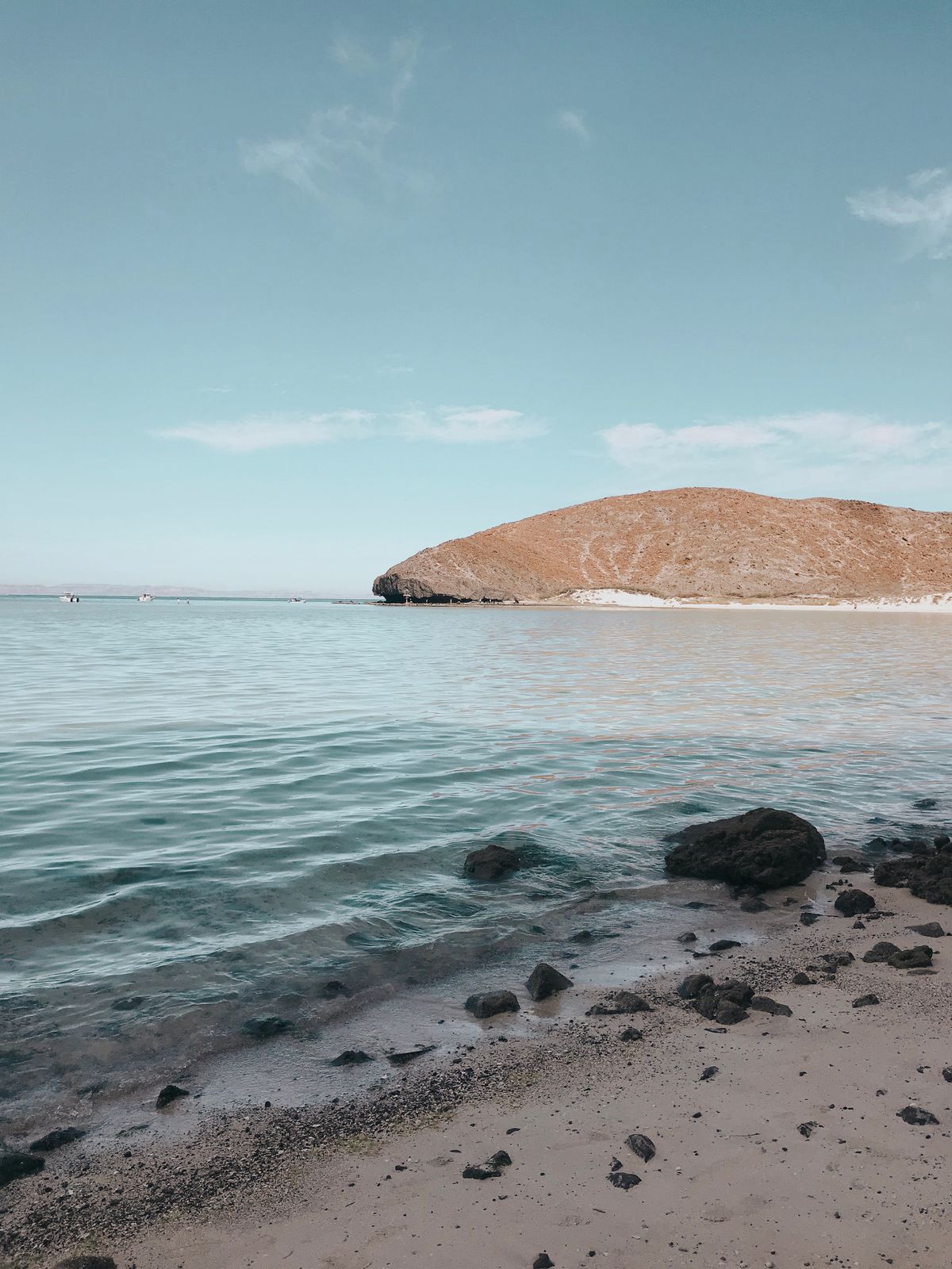 Tranquil beach scene at La Paz, Mexico with clear waters and distant island.