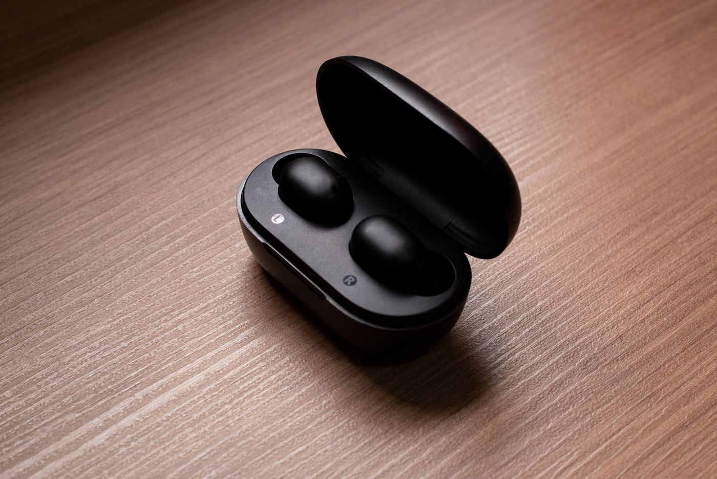 Wireless earbuds in an open charging case on a wooden surface