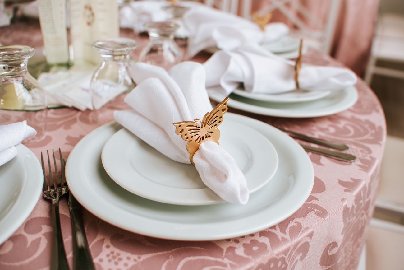 Elegant place setting with layered plates, napkin, cutlery, and floral details