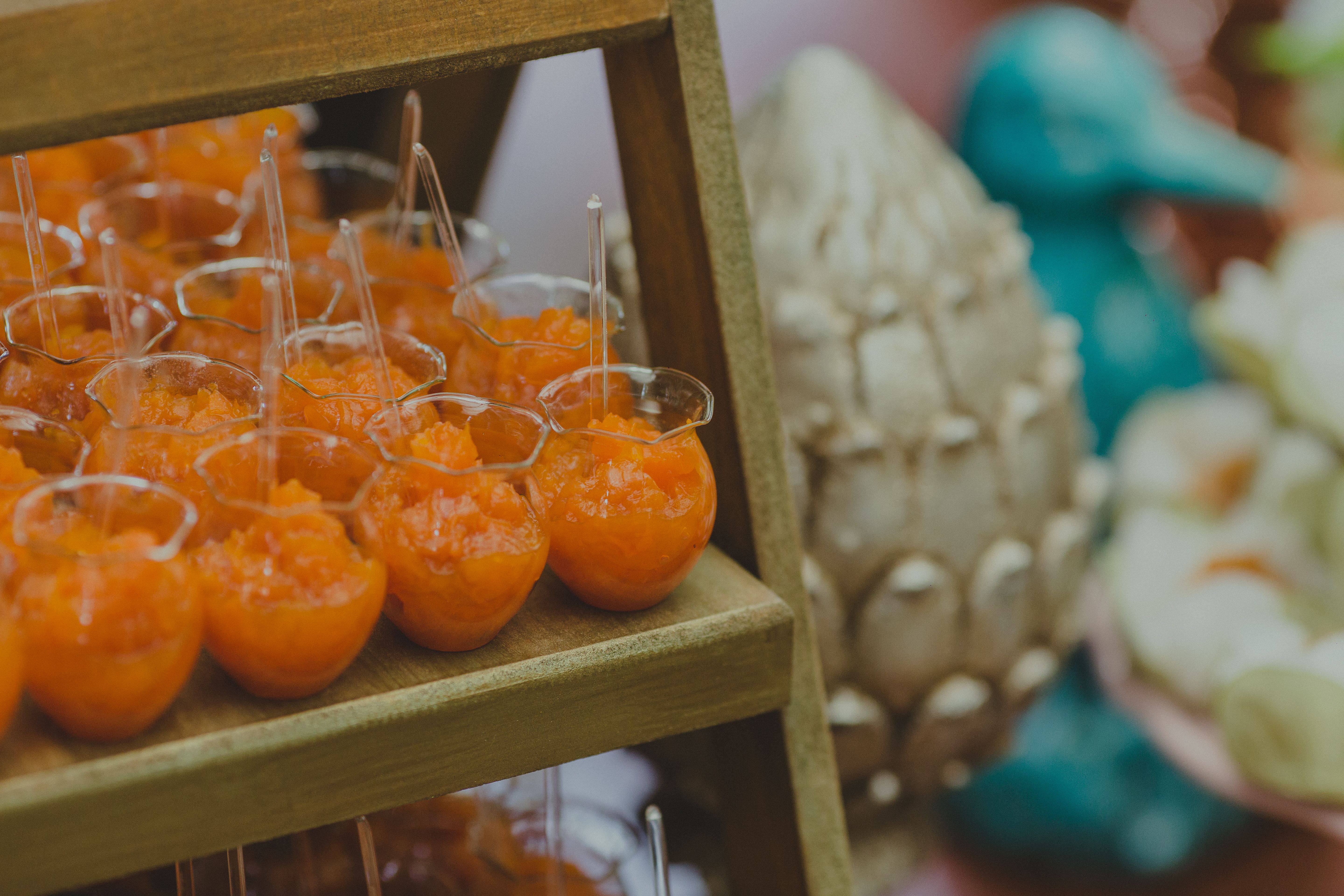Vibrant orange dessert cups arranged on a wooden shelf, offering a fresh and inviting appeal.