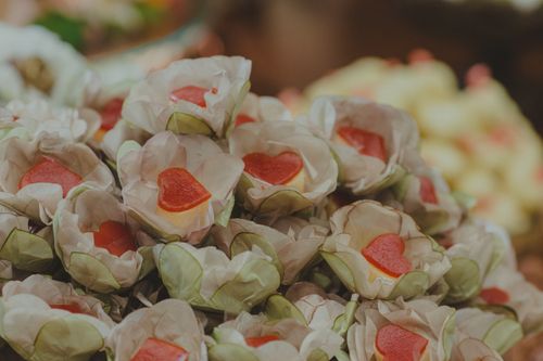 Free A close-up of heart-shaped candies elegantly wrapped in flower-shaped paper, perfect for weddings or romantic events. Stock Photo