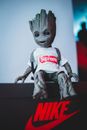 Modern collectible toy in stylish white t shirt with inscription and backpack placed on black cardboard box in light room