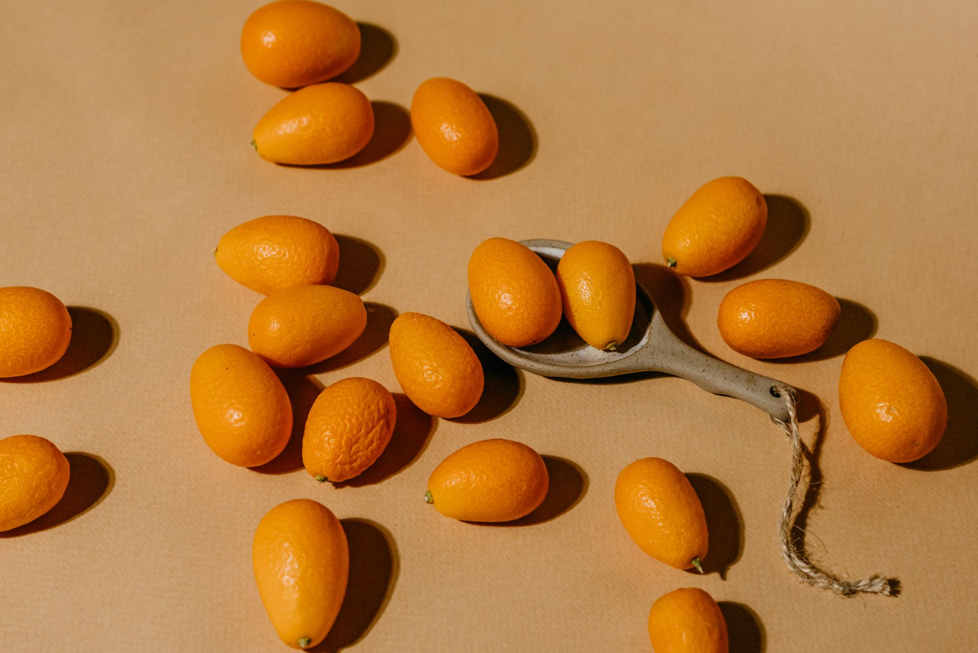 High-angle view of fresh kumquats on a rustic brown surface with natural shadows.