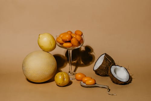 Free A Bunch of Kumquats in Martini Glass Beside Citrus Fruits and a Sliced Coconut Stock Photo