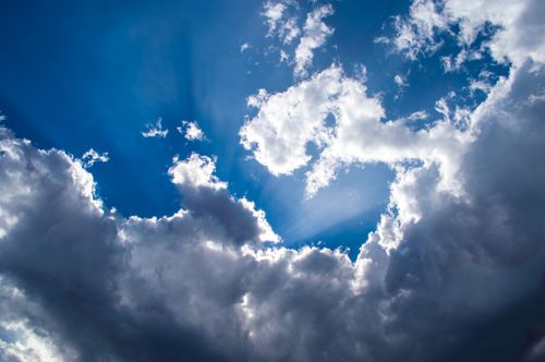 Free Captivating view of sunbeams breaking through dramatic clouds in a clear blue sky, evoking serenity. Stock Photo