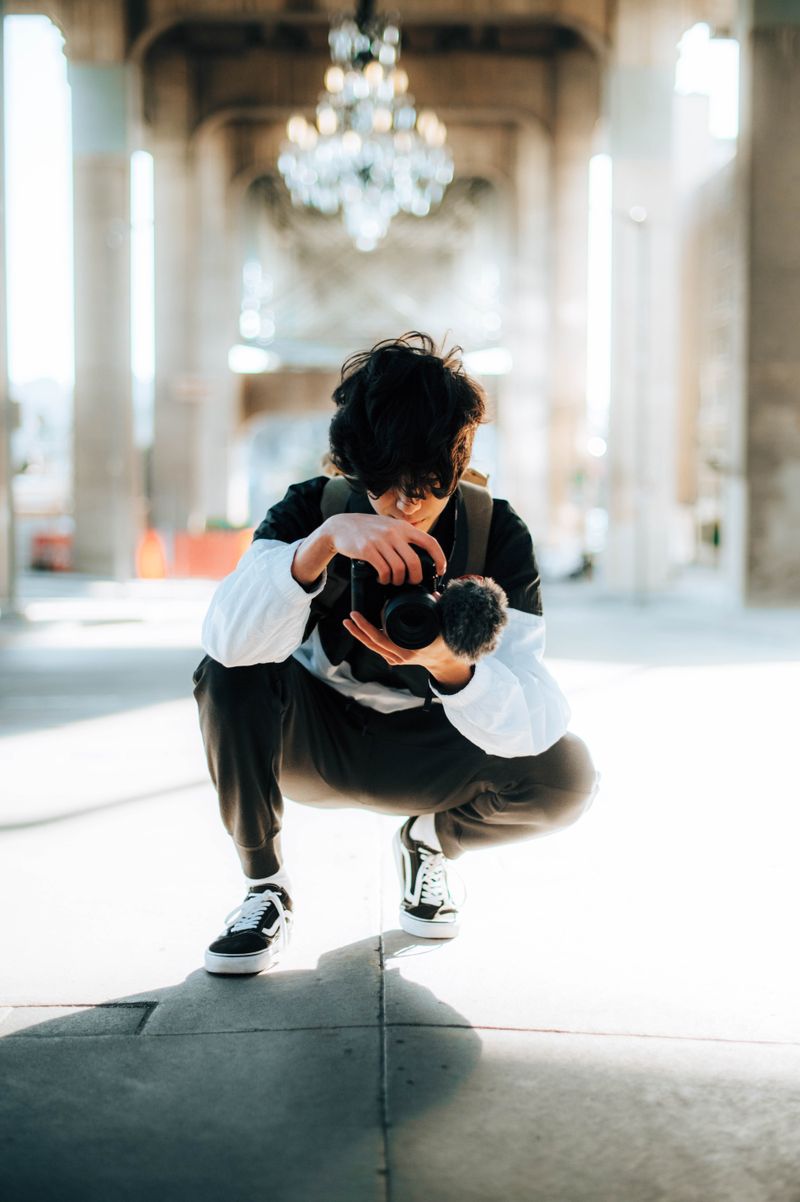 Photographer crouching on a sunlit street framing a shot
