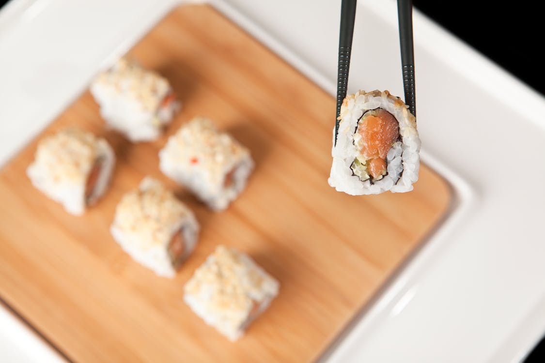 A Black Chopsticks Holding a Salmon Maki 