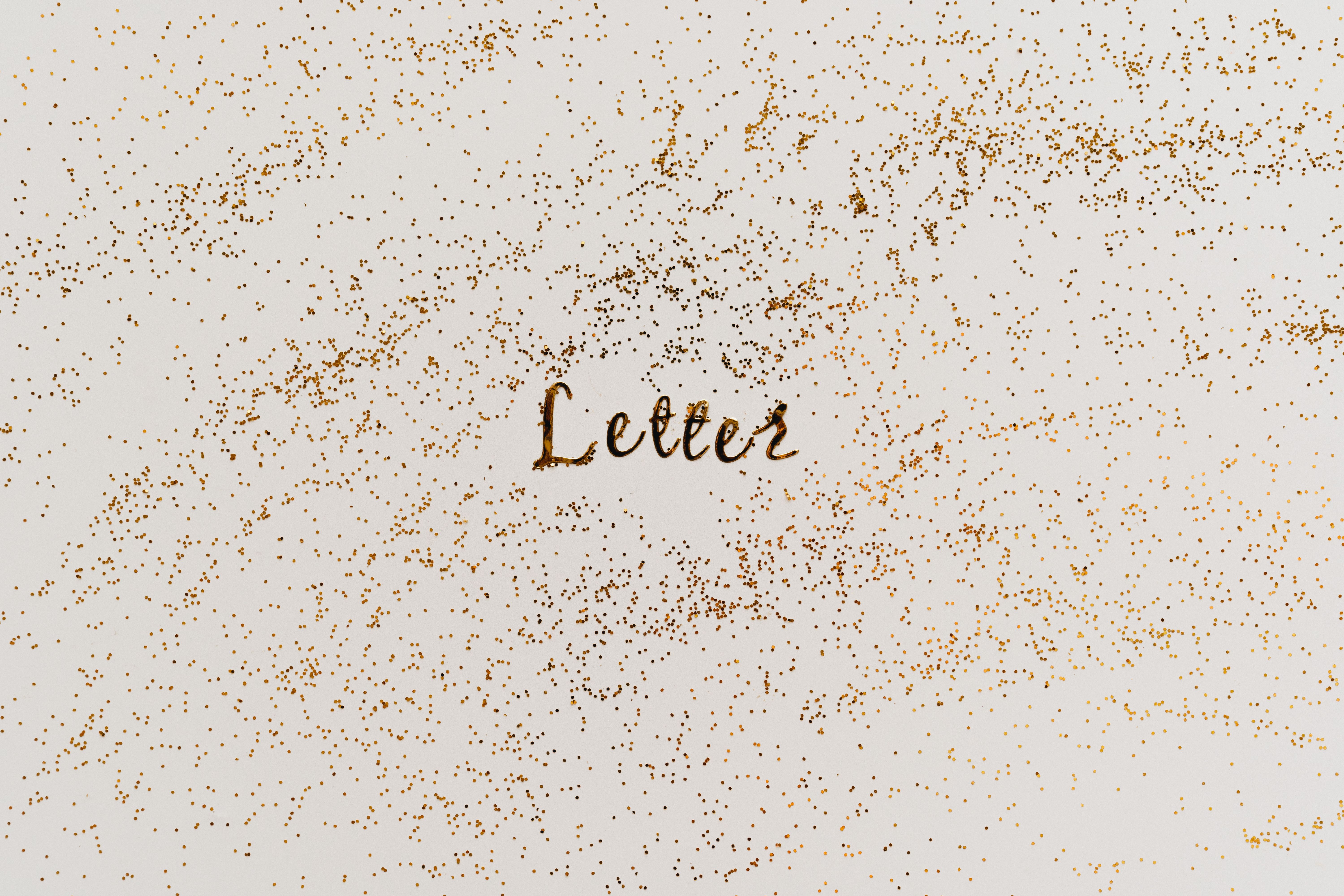 A textured artwork featuring the word 'Letter' amidst scattered gold glitter on a white background.