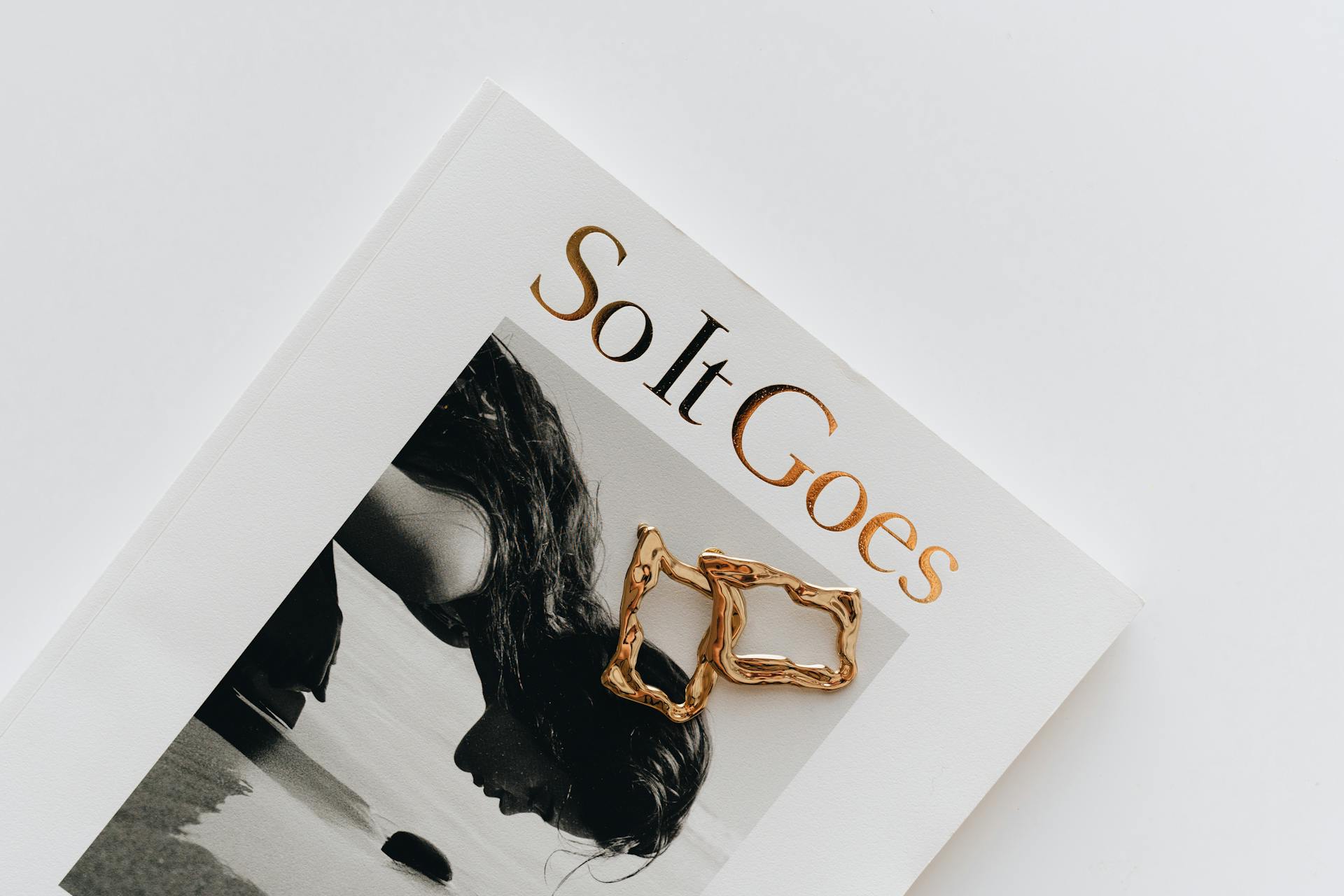 A minimalistic magazine layout featuring a gold bracelet placed elegantly on the cover.