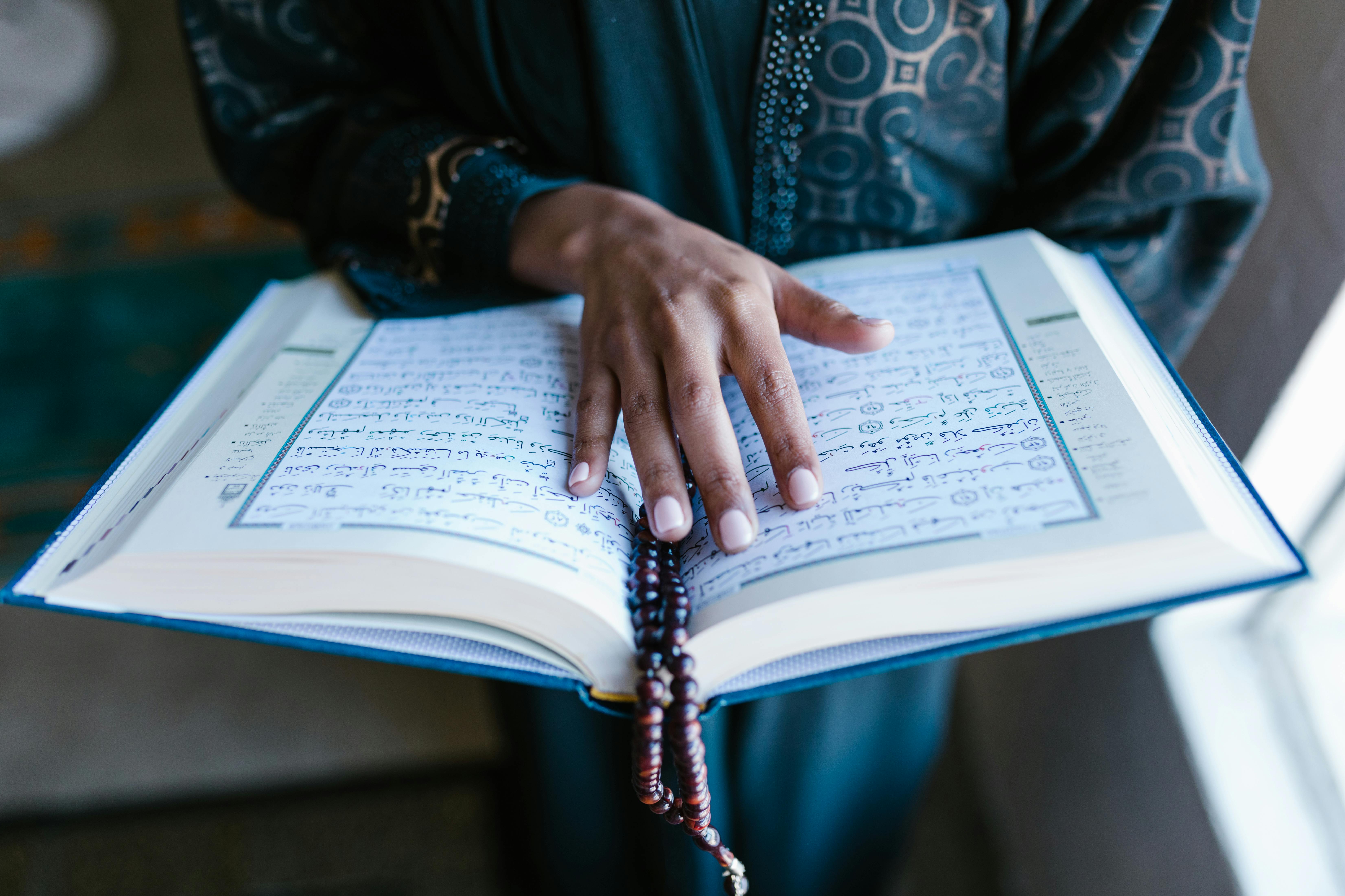 person in blue long sleeve shirt holding white book