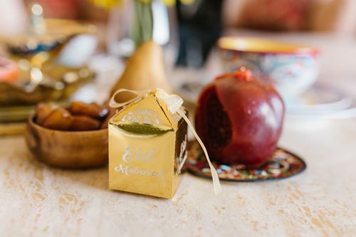 Free Warm and inviting Eid table setting with a decorative gift box, pomegranate, and traditional dishes. Stock Photo