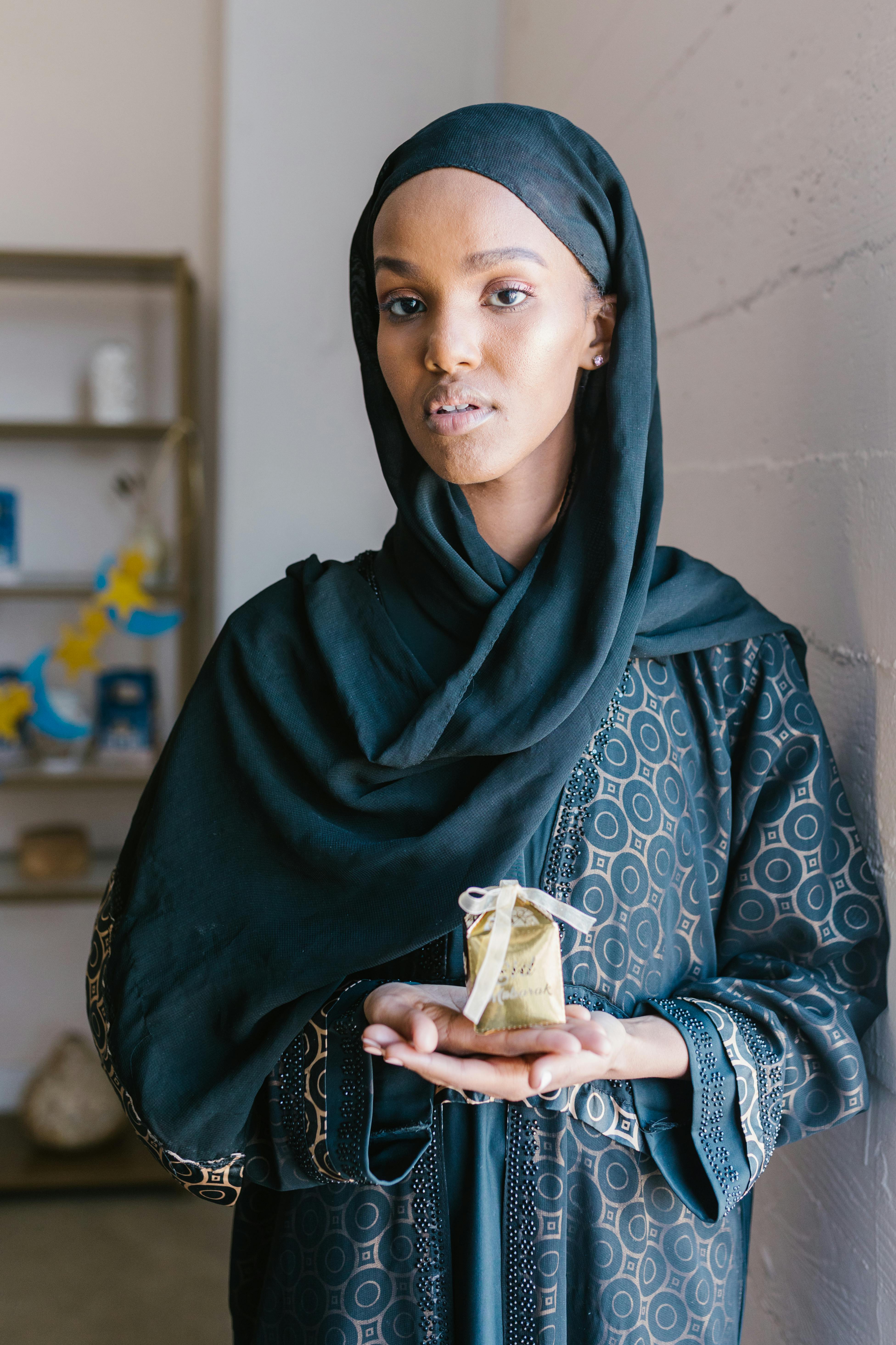 woman in black hijab holding white ceramic mug