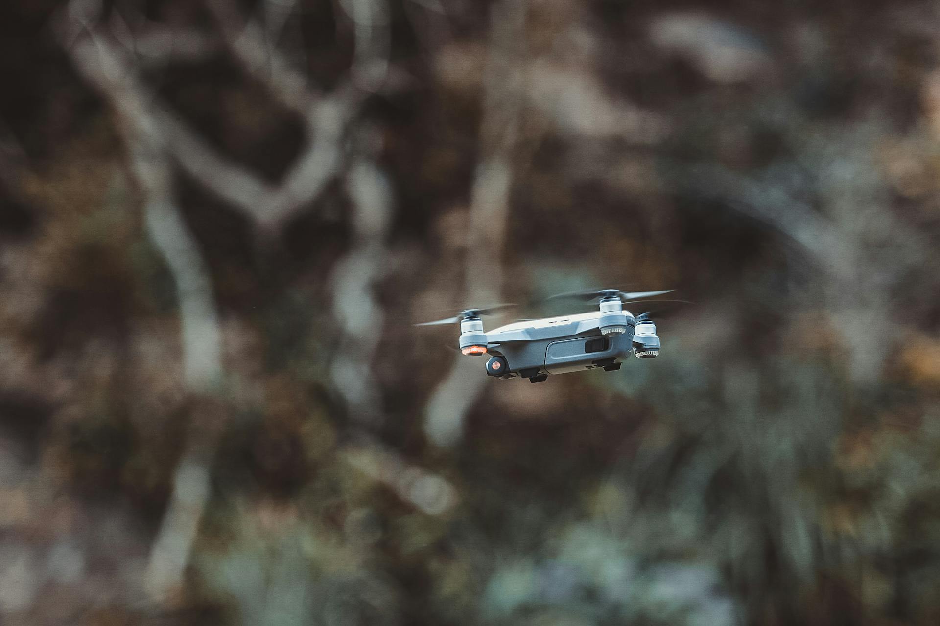 A sleek drone hovers in the wilderness, showcasing modern technology.