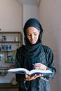A Woman in Hijab Holding a Book and Prayer Beads