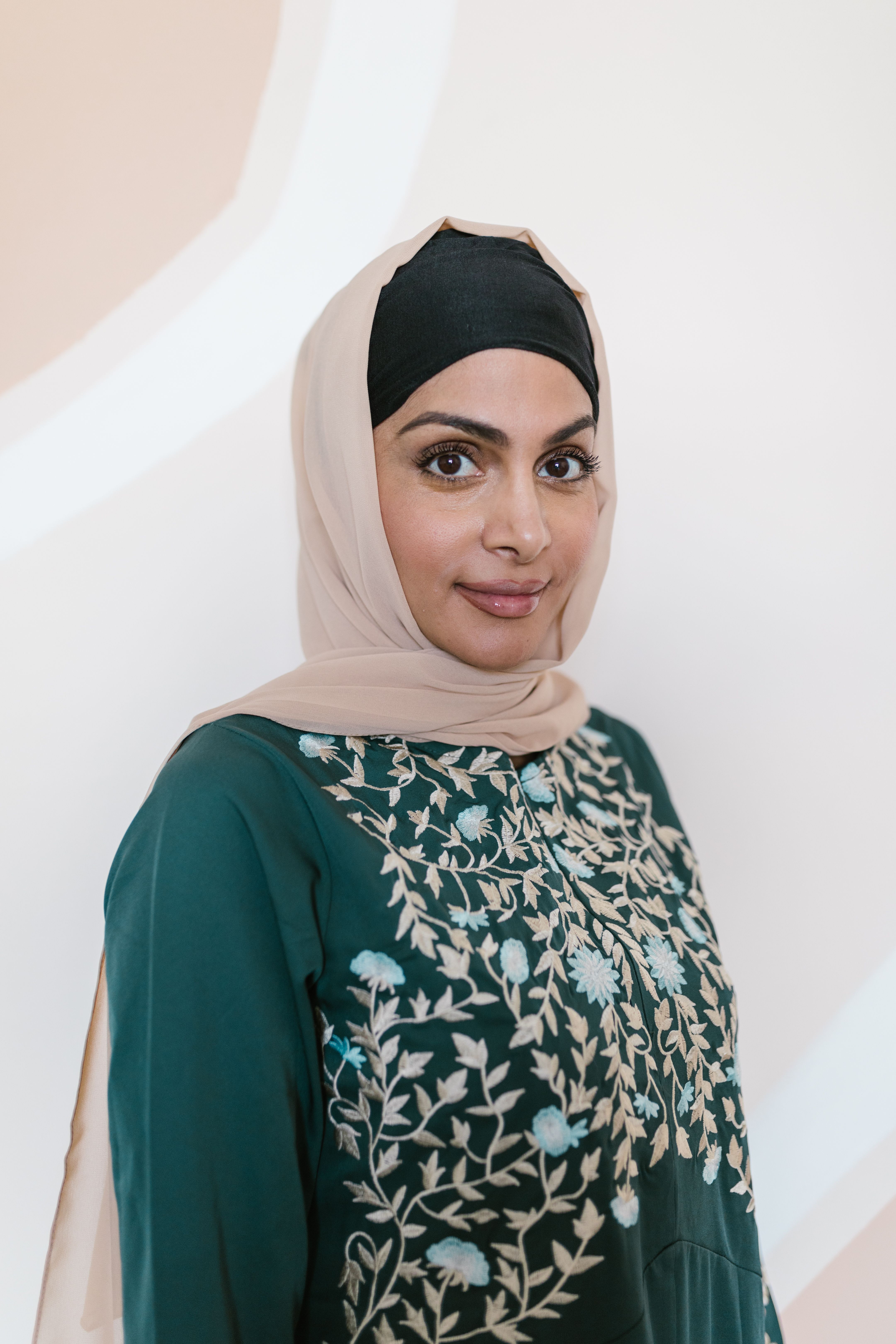 Close-up portrait of a smiling woman wearing a hijab and traditional embroidered dress.
