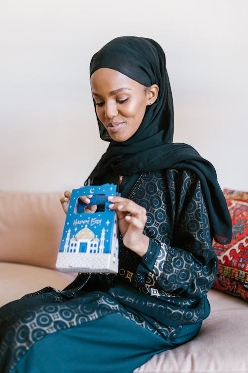 Woman in Black Hijab Holding Blue and White Box