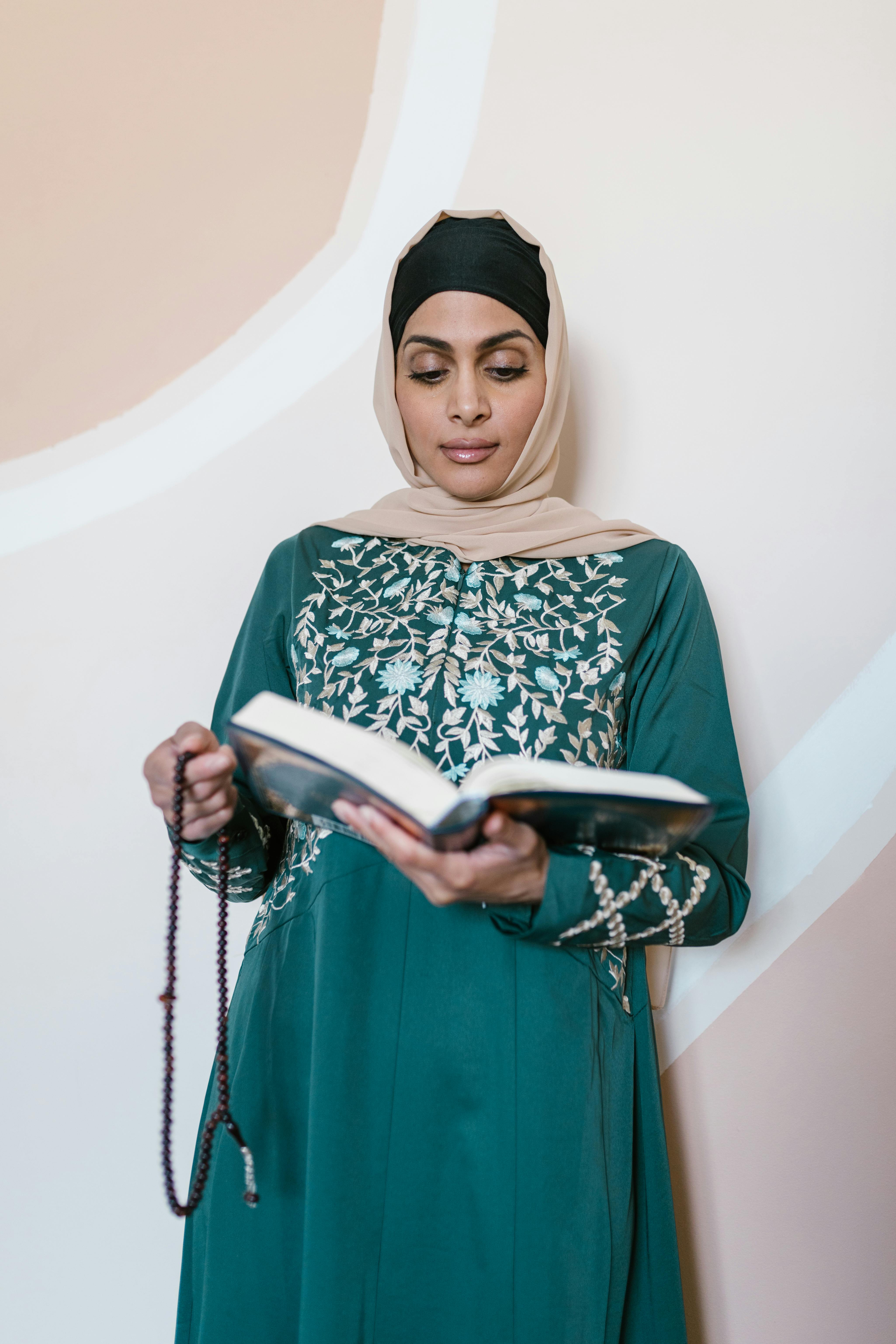 woman in green and white hijab holding a holy book