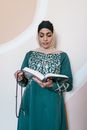 Woman in Green and White Hijab Holding A Holy Book