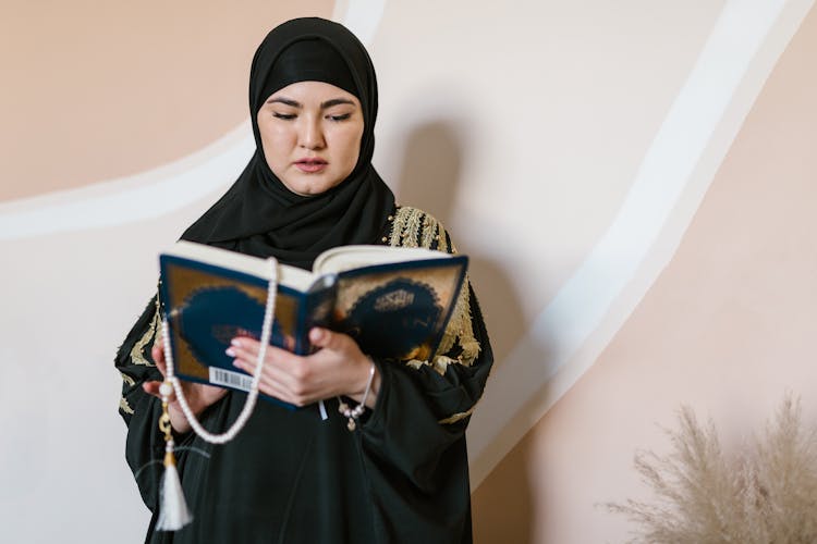 Woman In Black Hijab Holding A Holy Islam Book