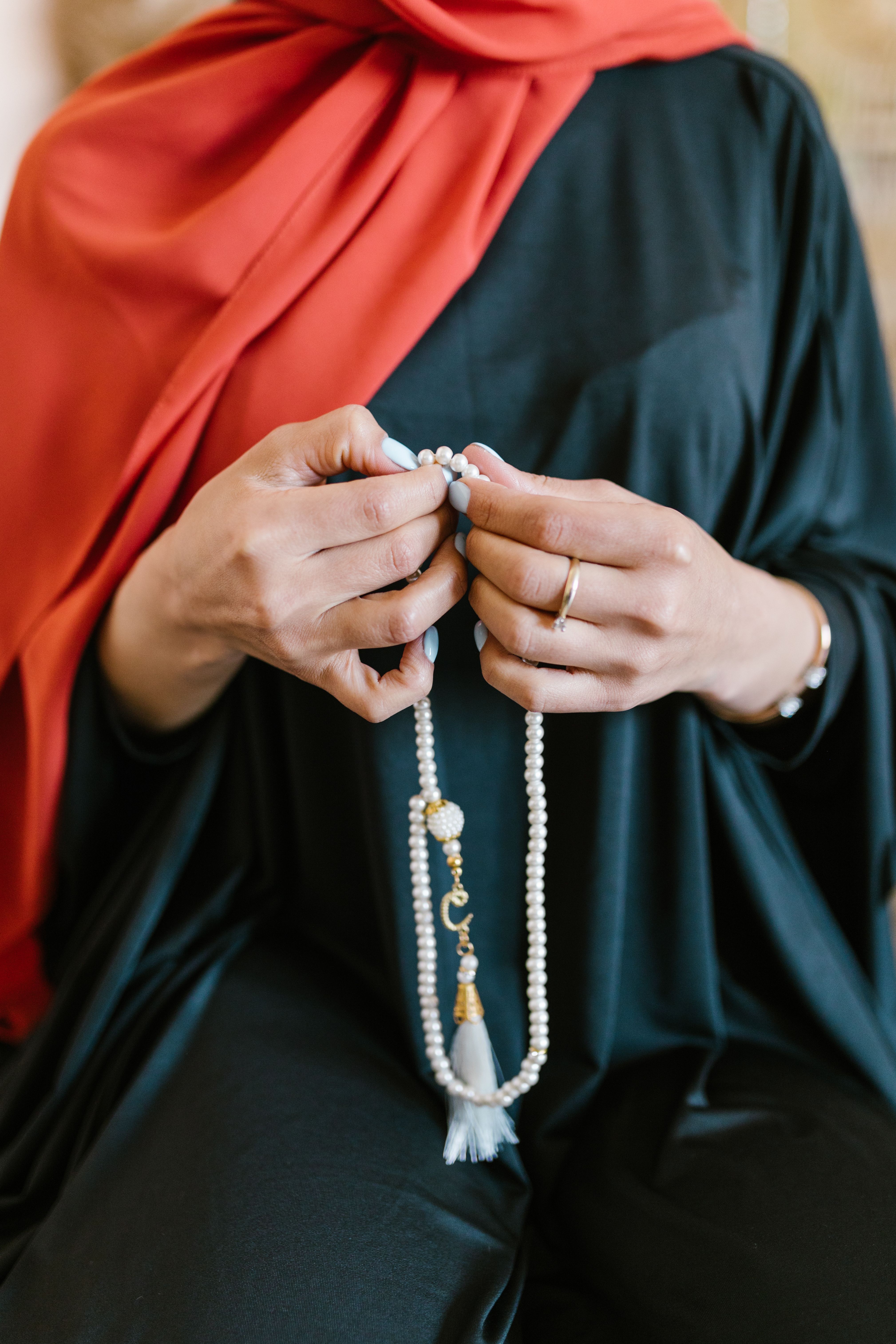 A Person in Black and Red Abaya Holding Prayer Beads · Free Stock Photo