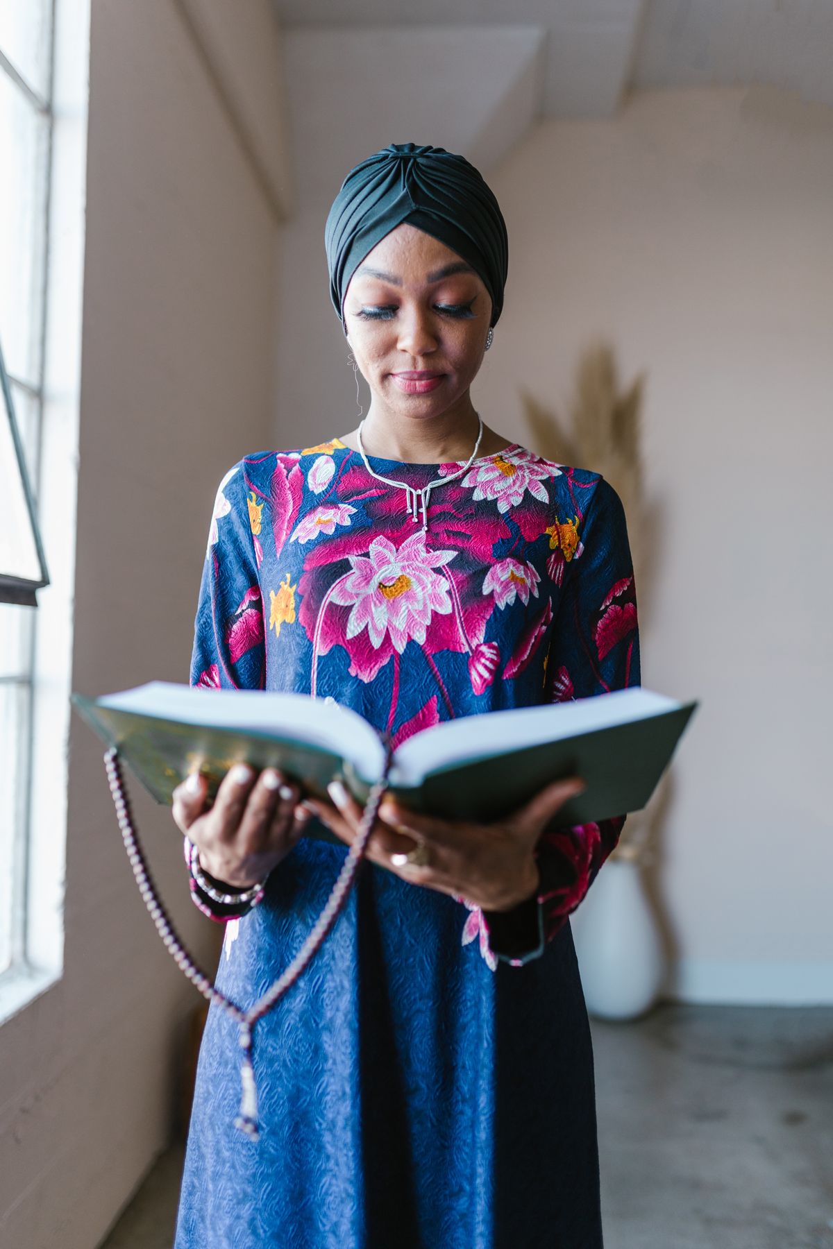 Woman in hijab reading Quran indoors