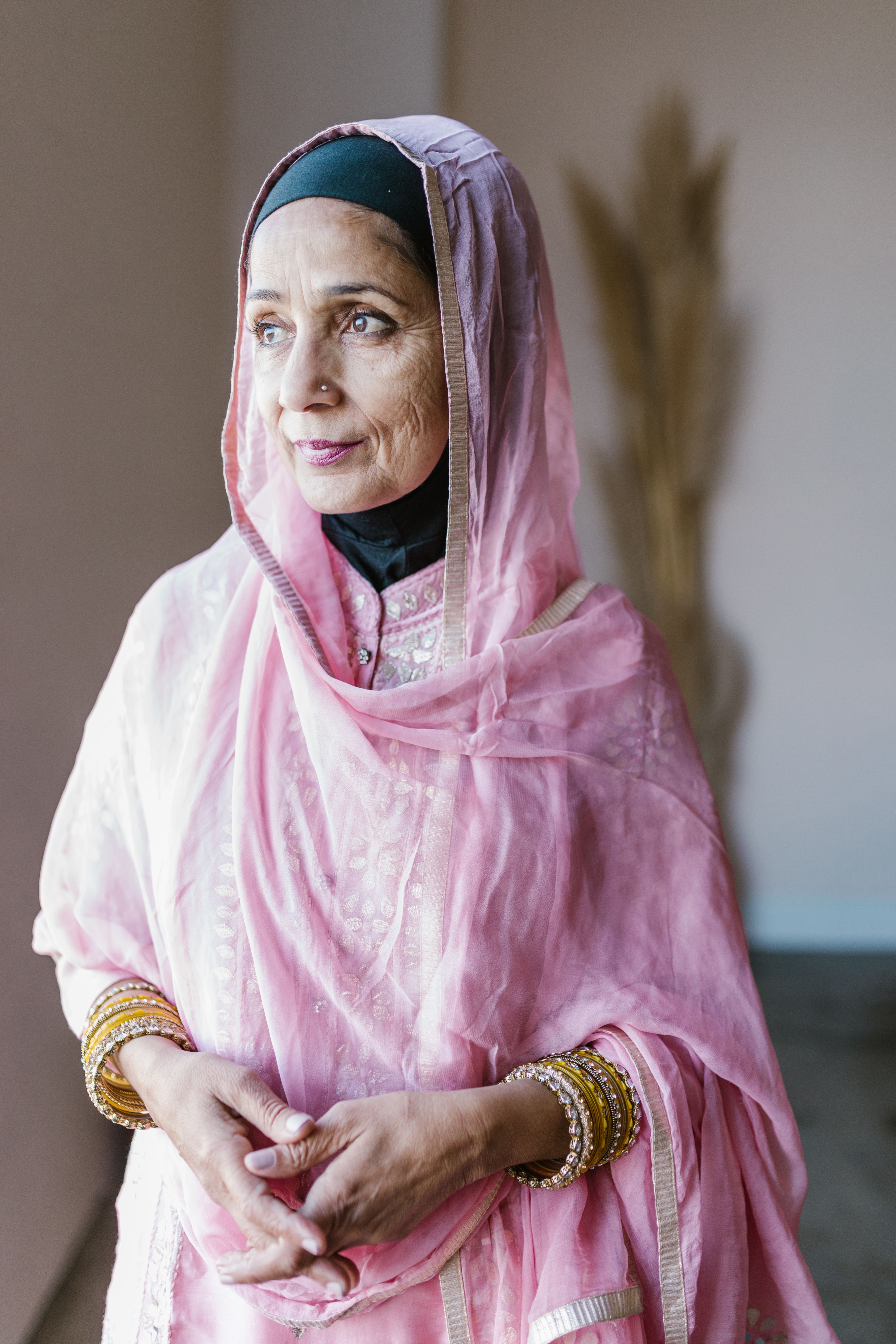 Portrait of a senior woman in traditional pink attire with a shawl, gazing thoughtfully.