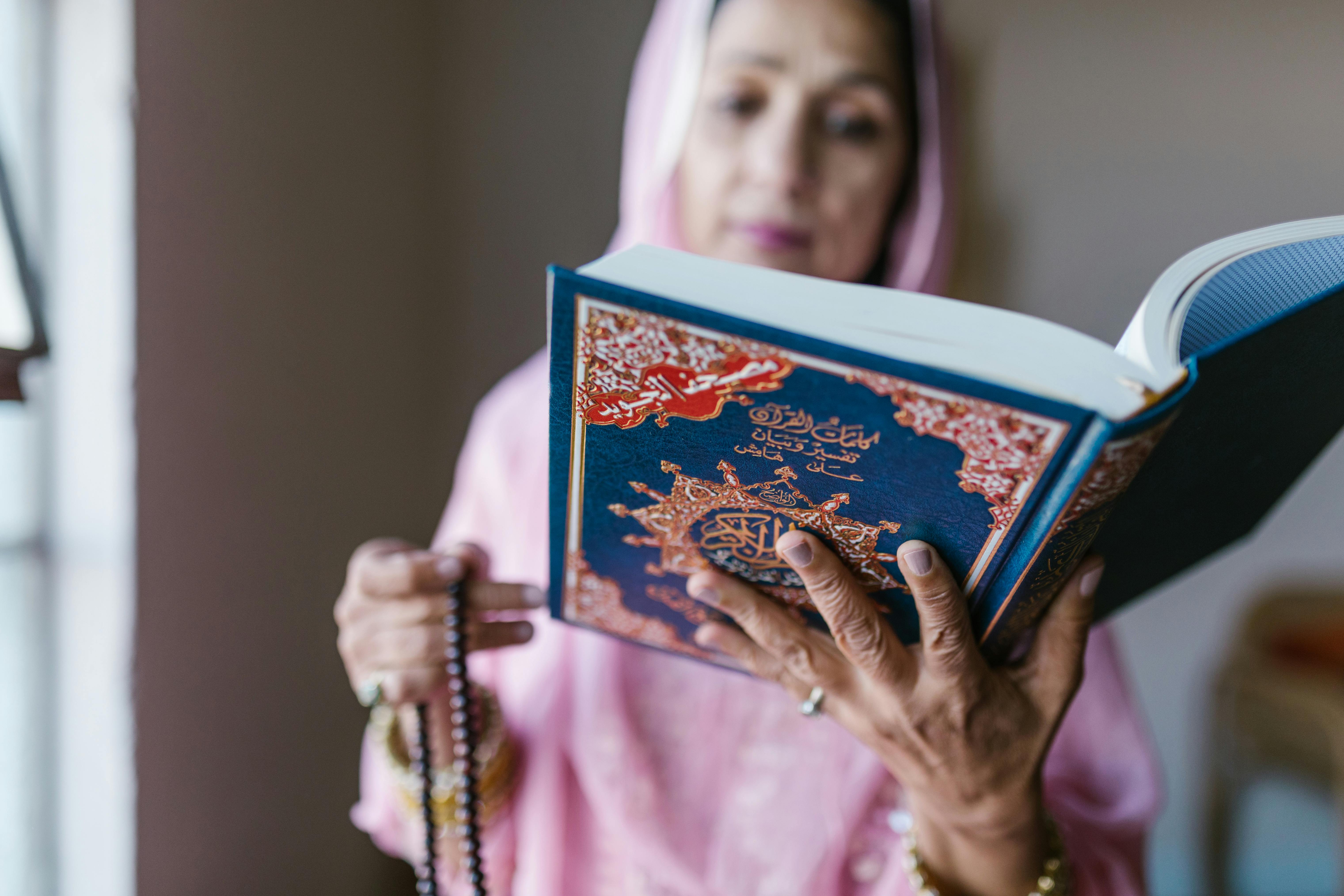 woman in pink hijab holding blue book