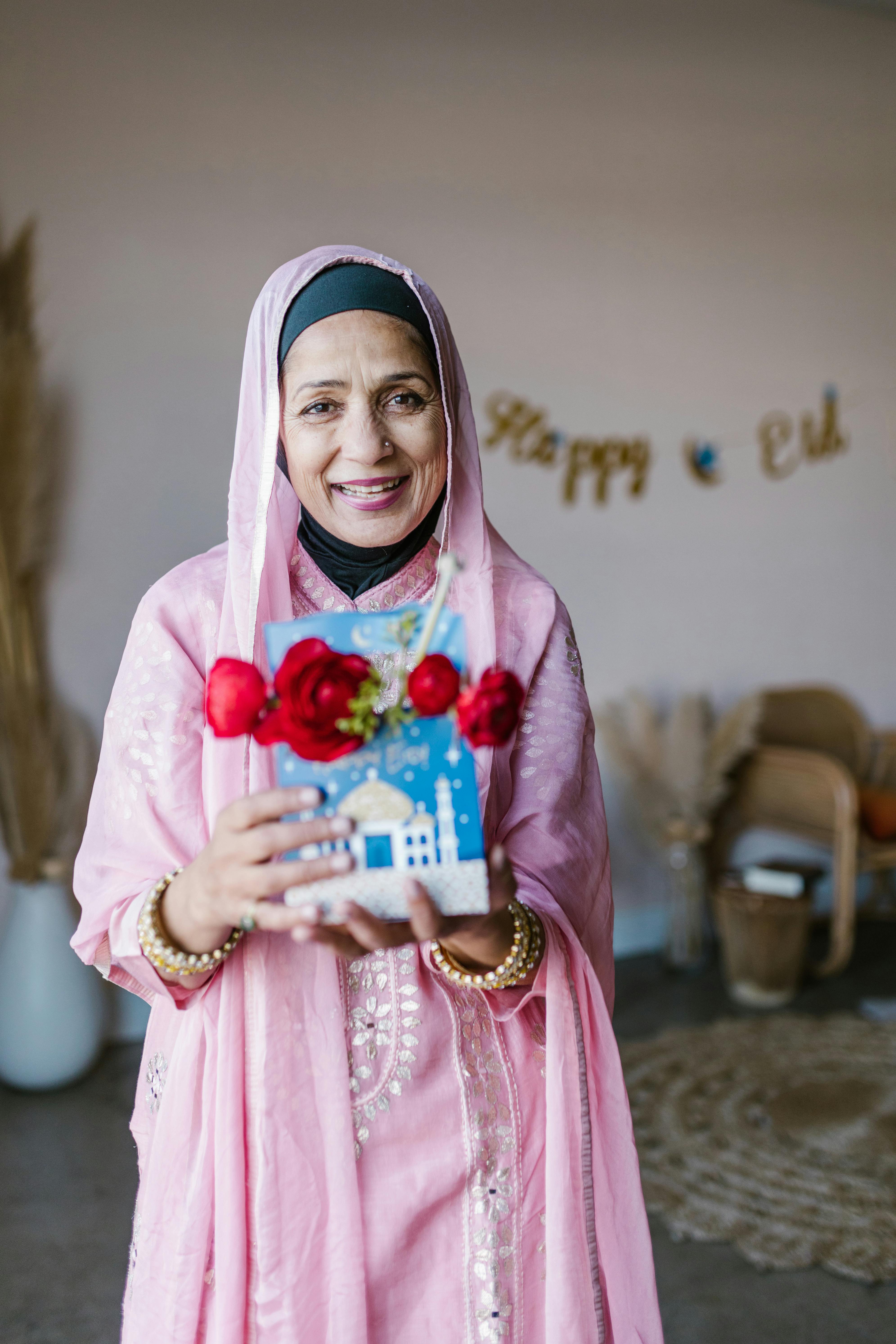 woman in pink hijab holding red and white bouquet of flowers
