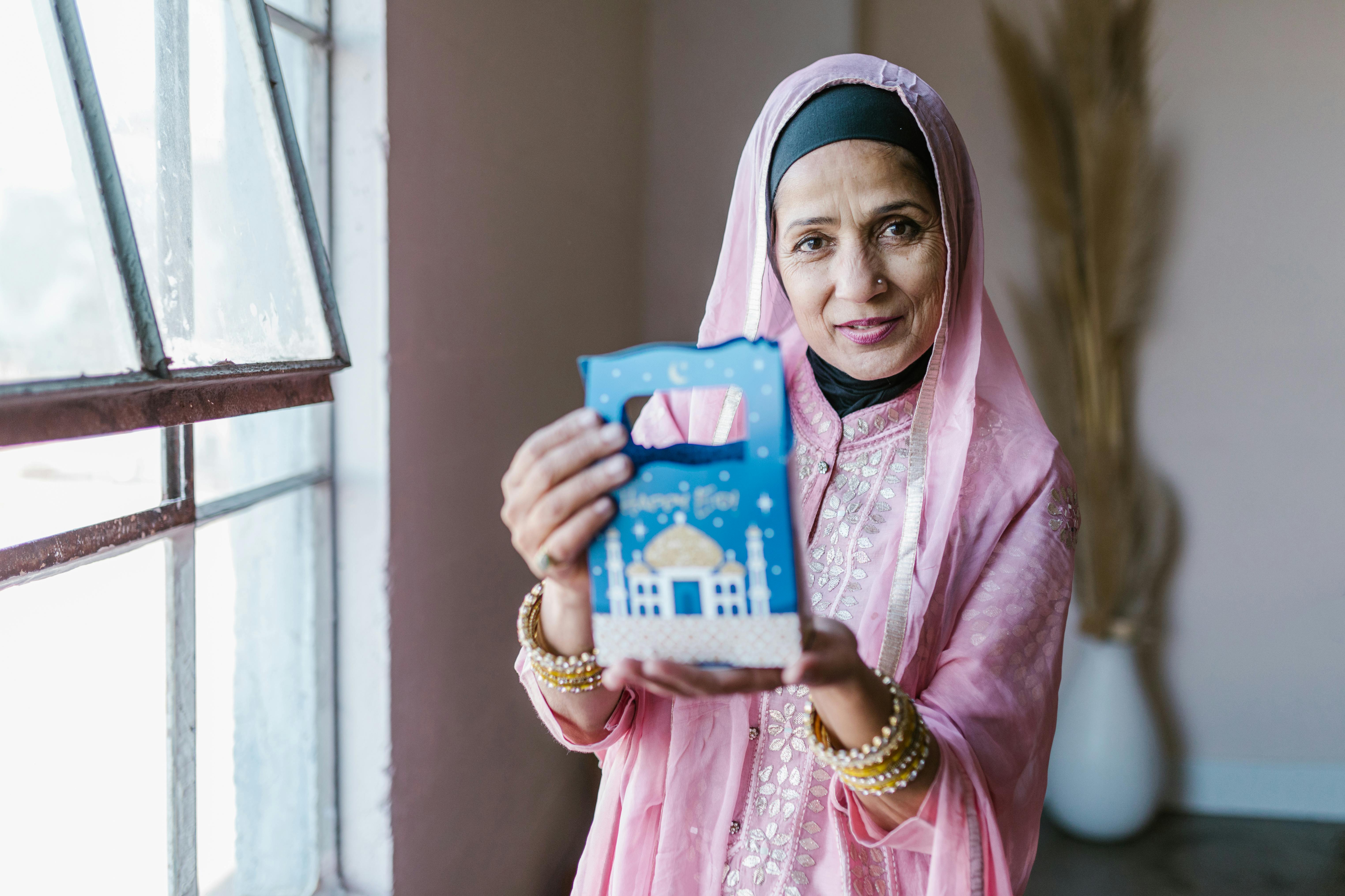 woman in pink hijab holding blue and white plastic pack