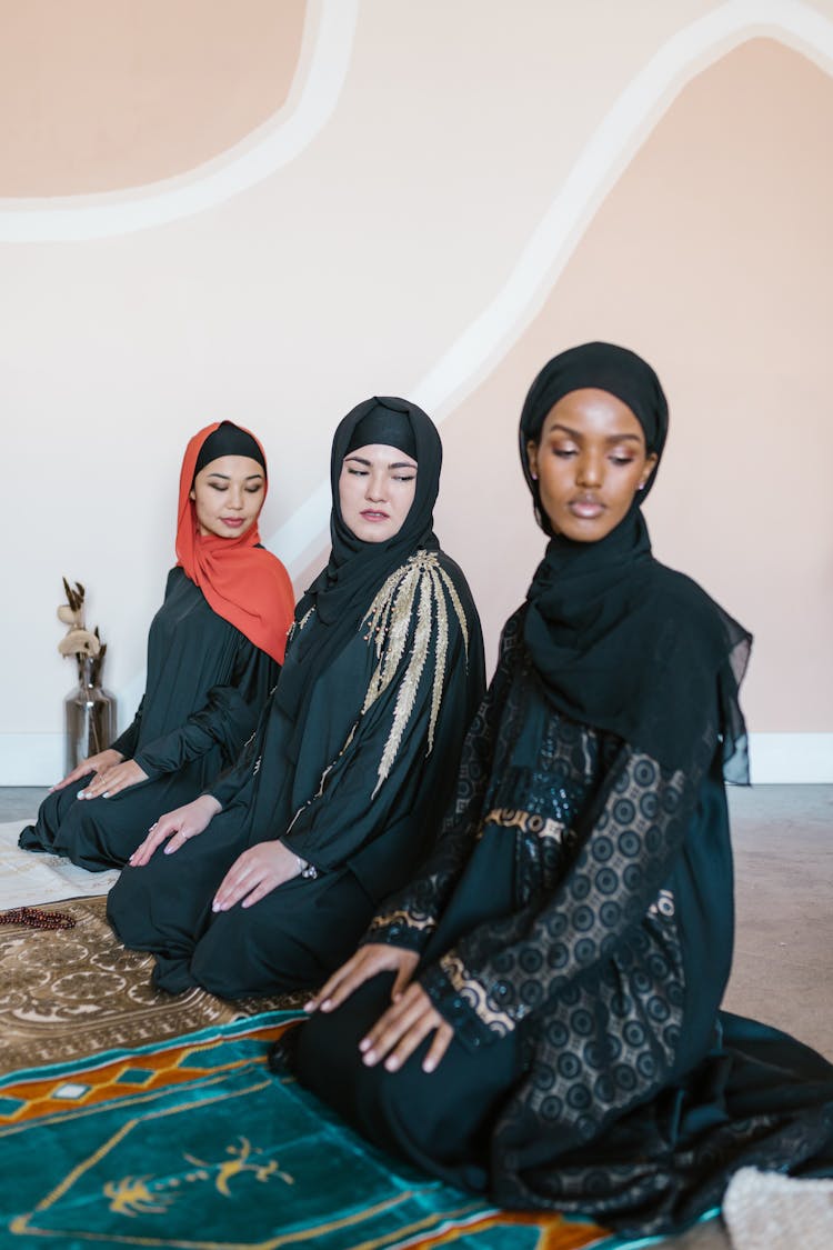 Women Wearing Hijabs Kneeling On Rugs