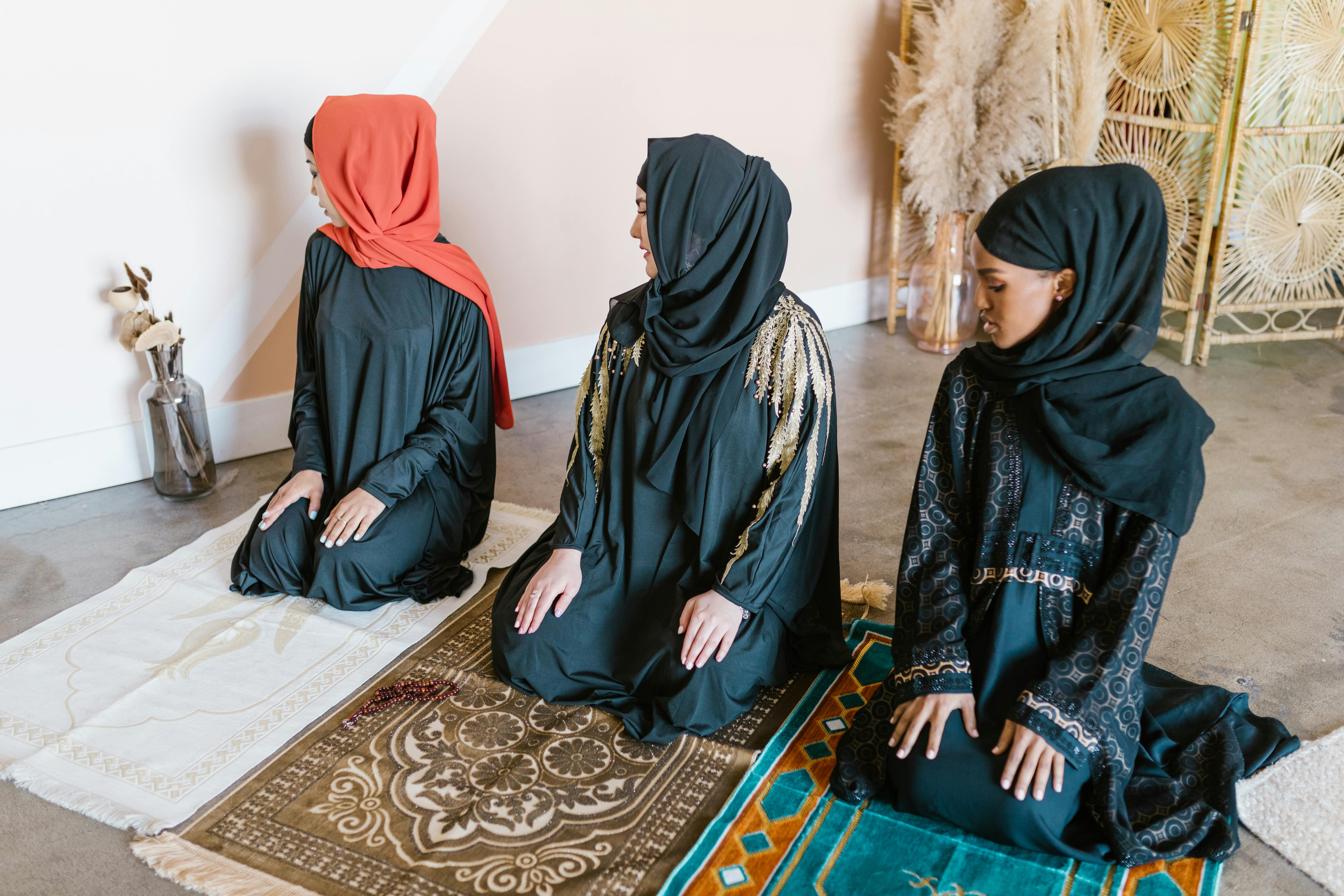 woman in black hijab sitting on blue and brown area rug