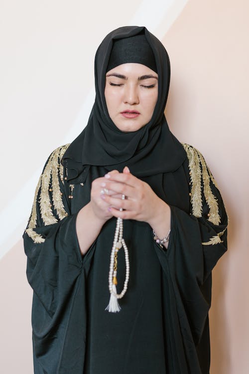 Woman in Black Hijab and Traditional Dress Holding a Prayer Beads