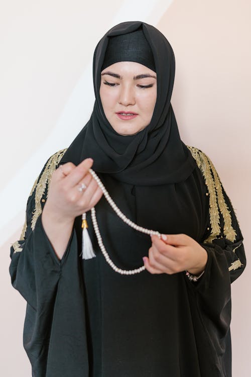 Woman in Black Hijab Holding a White Prayer Beads