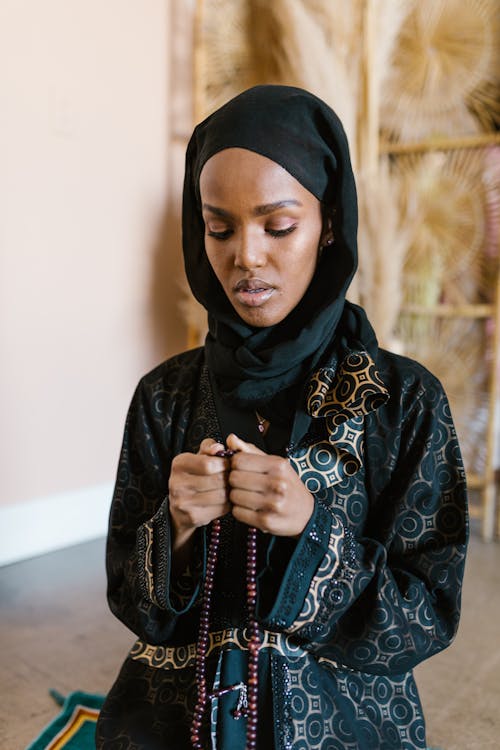 A Woman in Traditional Dress and Hijab Praying