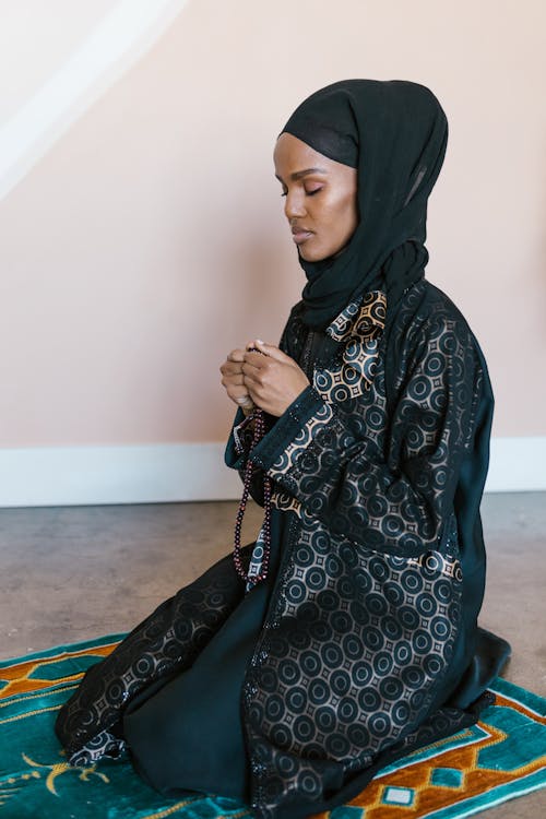 Woman in Black Traditional Clothing Holding Brown Prayer Beads