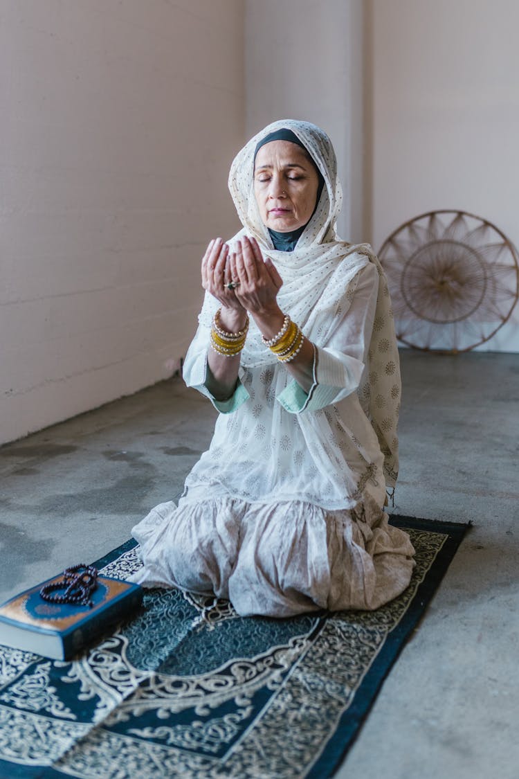 Woman In White Hijab Kneeling On A Prayer Rug