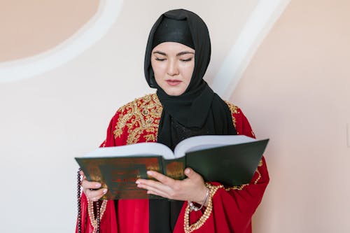 Woman in Black Hijab Holding Book